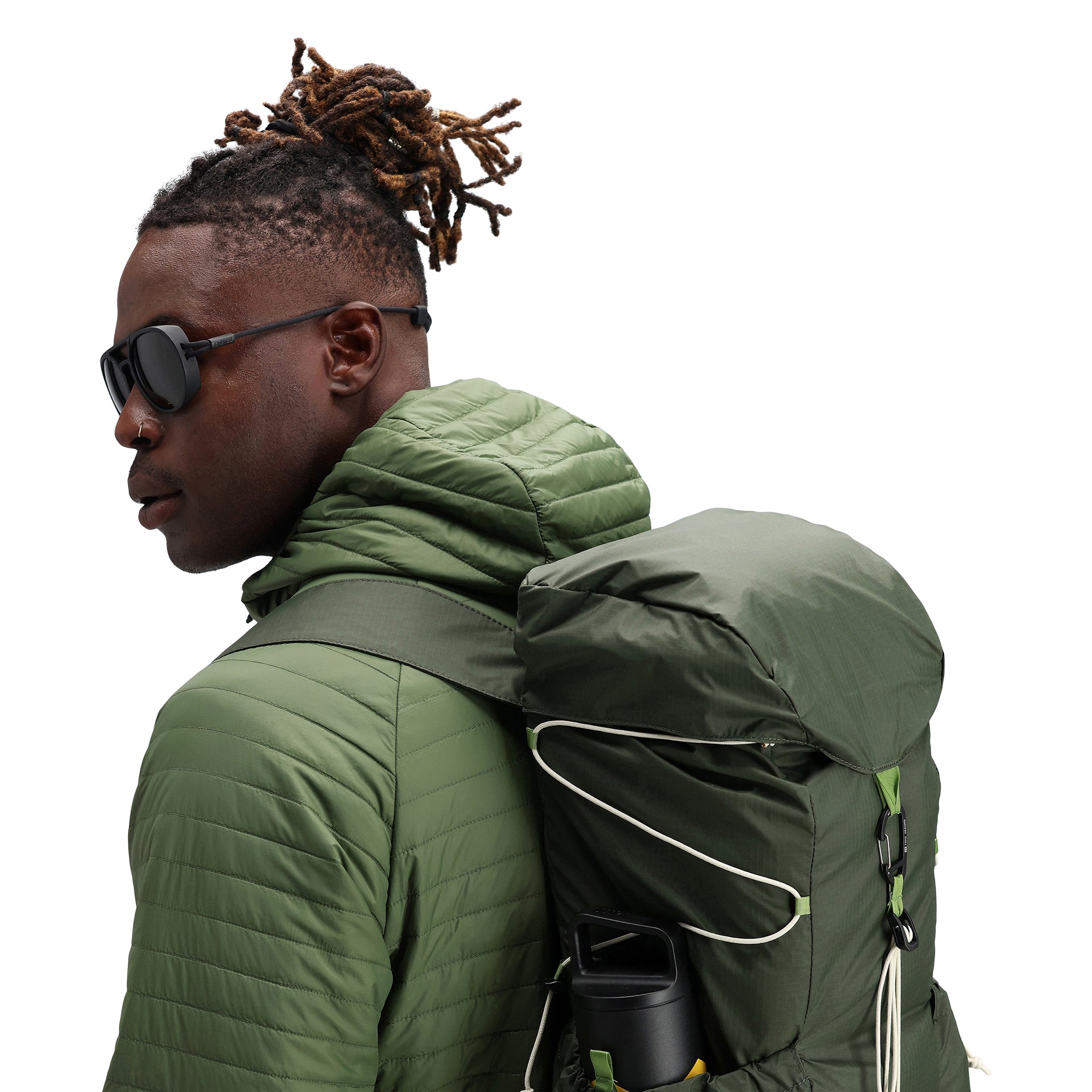 Model wearing Topo Designs TopoLite Cinch Pack 16L packable daypack backpack for travel in "olive" green.