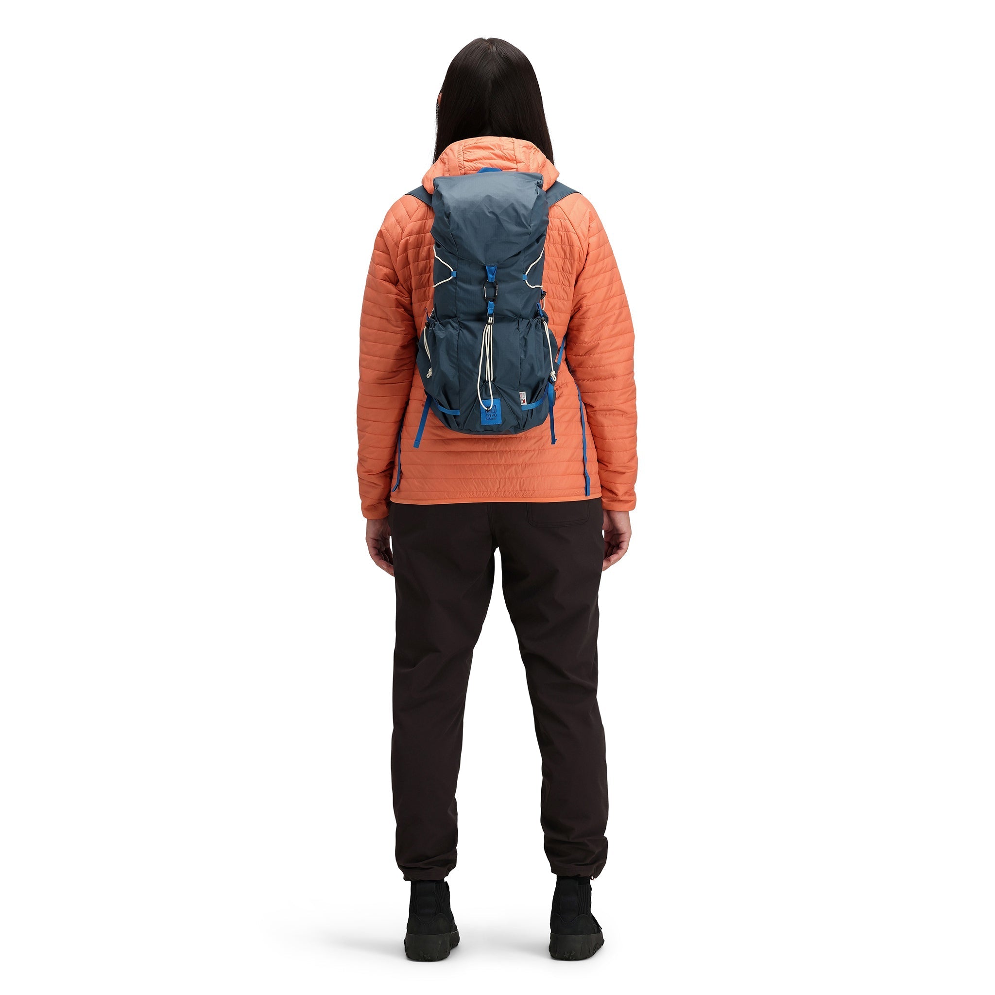 Model wearing Topo Designs TopoLite Cinch Pack 16L packable daypack backpack for travel in "pond blue"