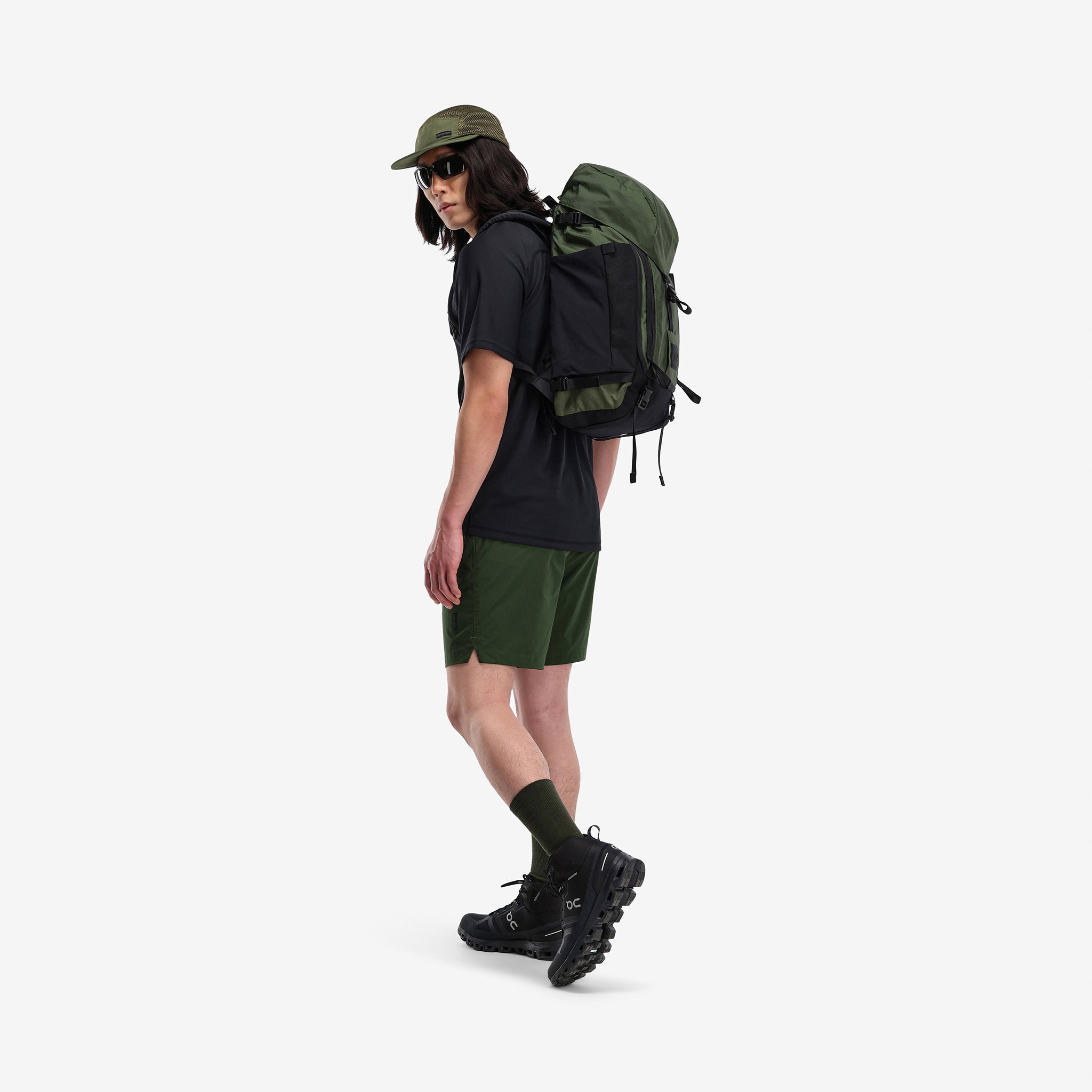 Model wearing Topo Designs Mountain Pack 28L hiking backpack with external laptop sleeve access in lightweight recycled "olive" green nylon.