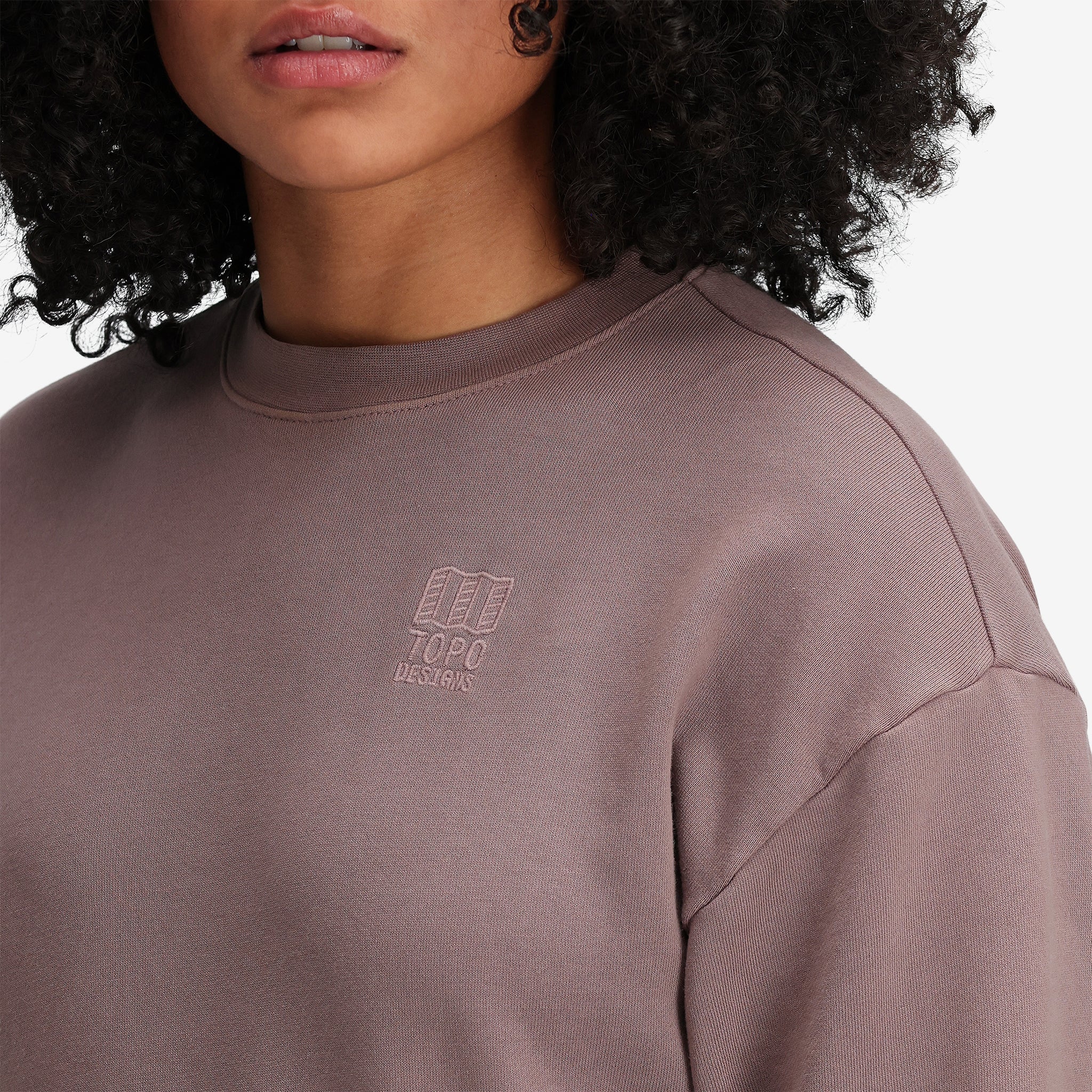 Detail shot of Topo Designs Women's Dirt Crew sweatshirt in 100% organic cotton French terry in "Peppercorn" purple brown. Show on "sage".