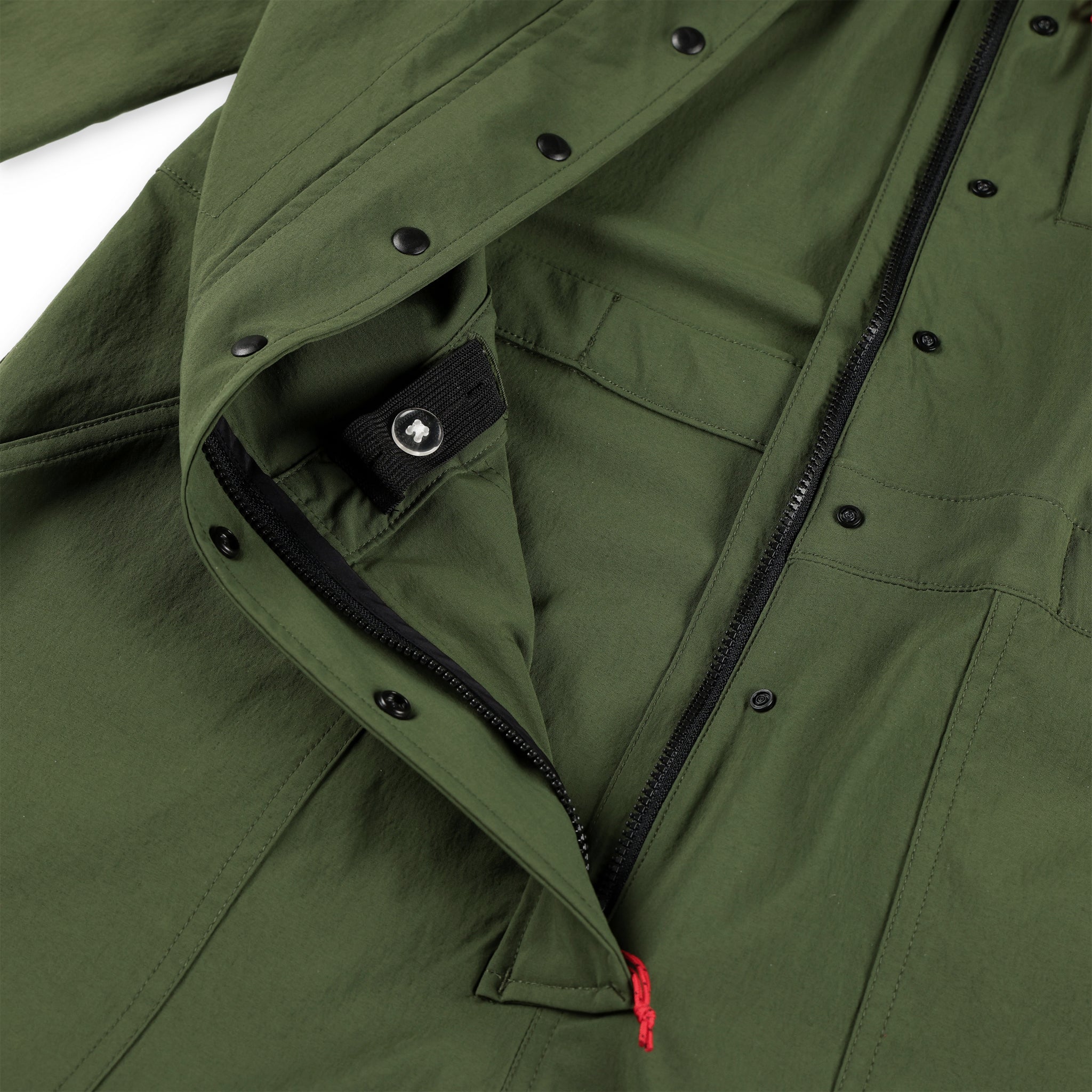 Detail shot of the Topo Designs Women's Coverall in olive green showing zipper opening, snap closures and internal waist band adjustment.