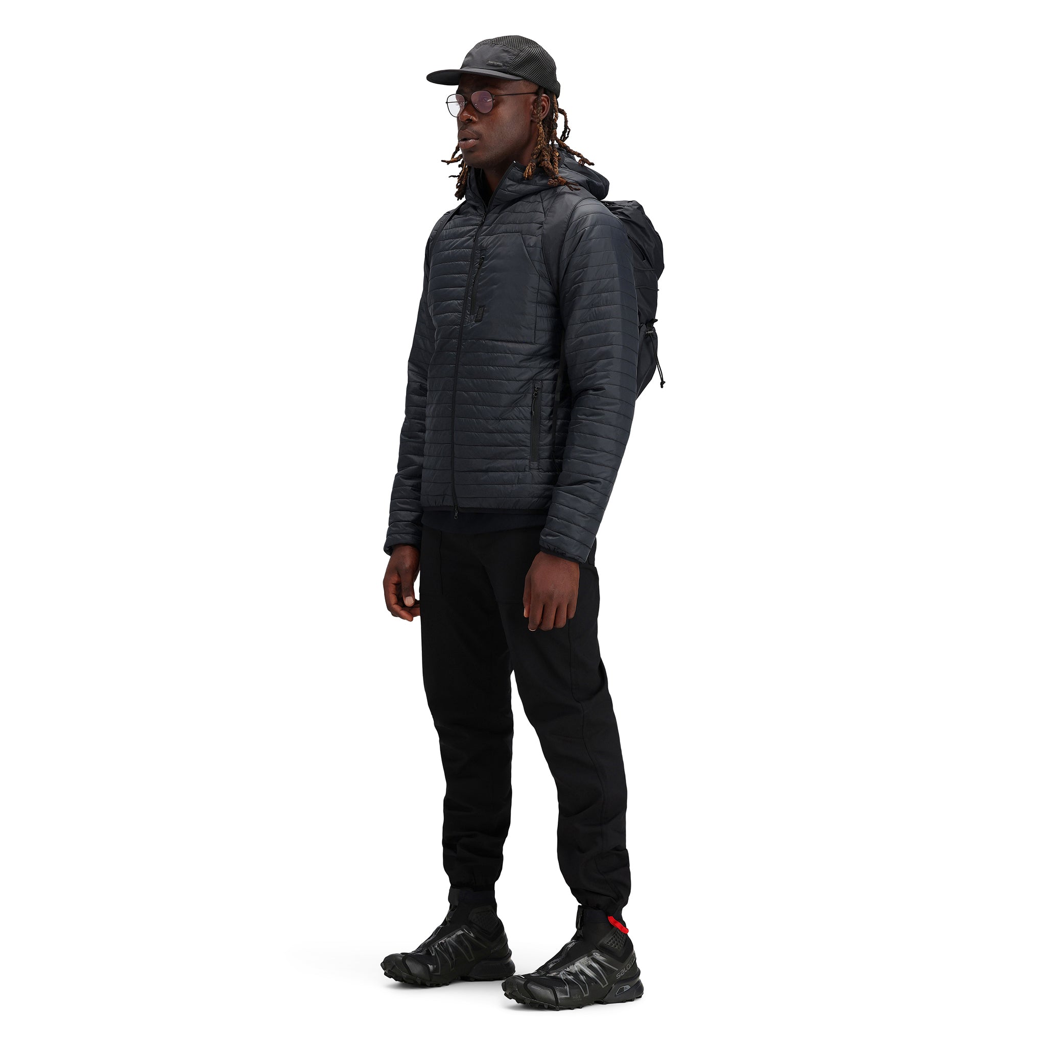 Model wearing Topo Designs Men's Global Puffer packable recycled insulated Hoodie jacket in "black"