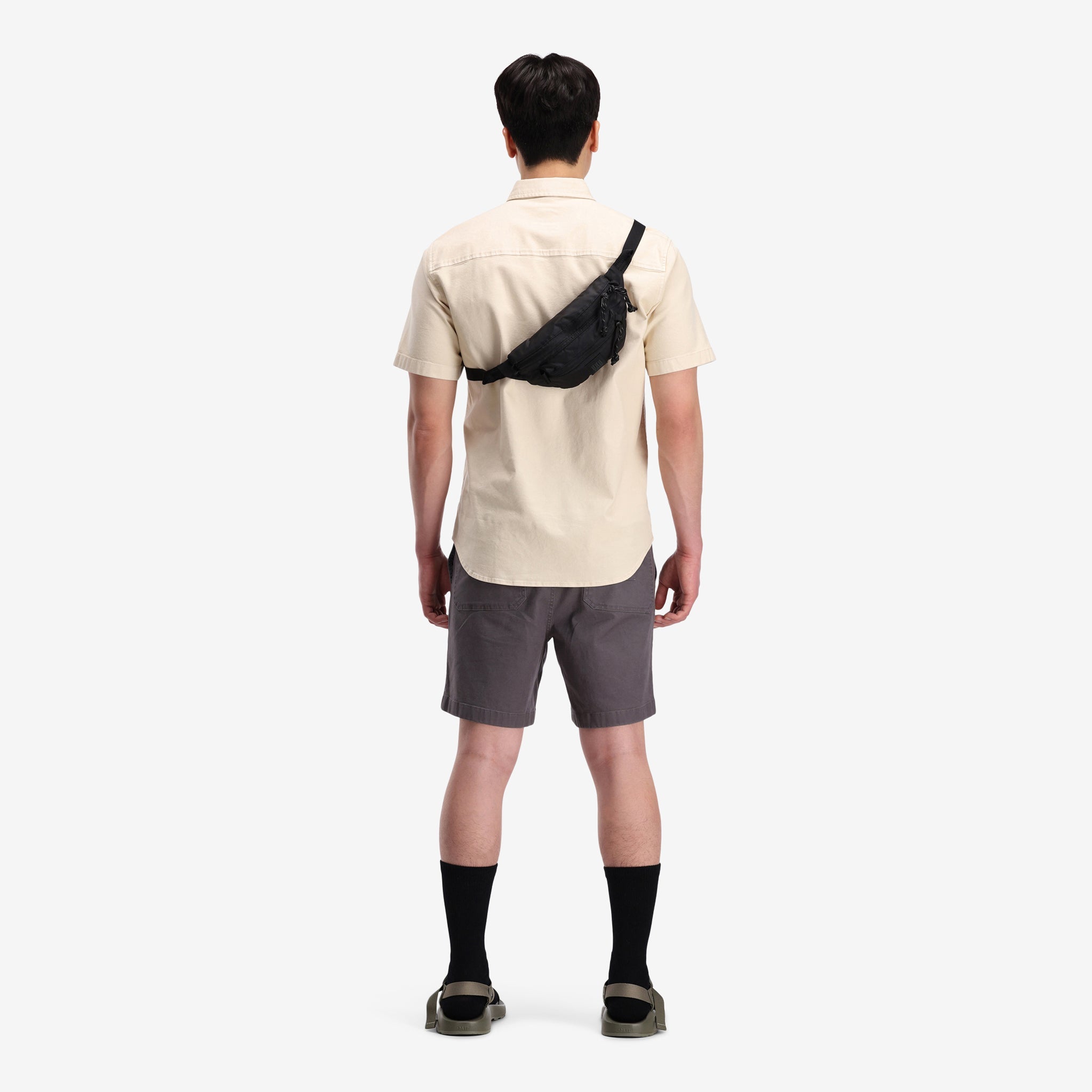 General on model shot, crossbody view of Topo Designs Mountain Waist Pack in lightweight recycled "Black / Black" nylon.